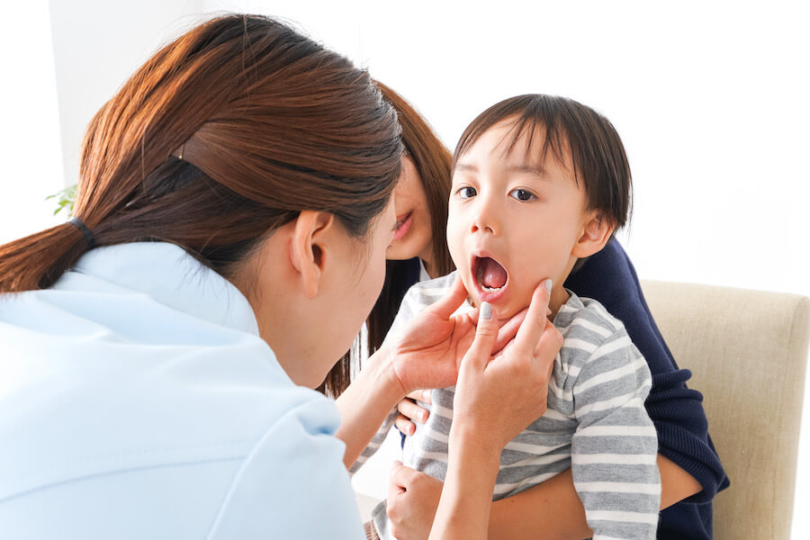 A dentist examines the inside of a brunette child's mouth