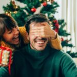 Woman giving man a gift for Christmas with article about replacing missing teeth before the holidays at Southern Dental Munford