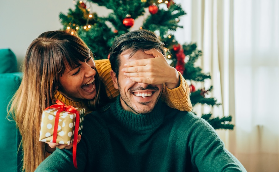 Woman giving man a gift for Christmas with article about replacing missing teeth before the holidays at Southern Dental Munford