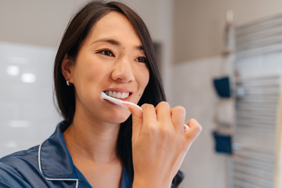 woman brushing her teeth to prevent enamel erosion and wear