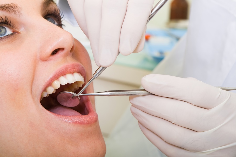 young woman getting oral cancer screening at the dentist
